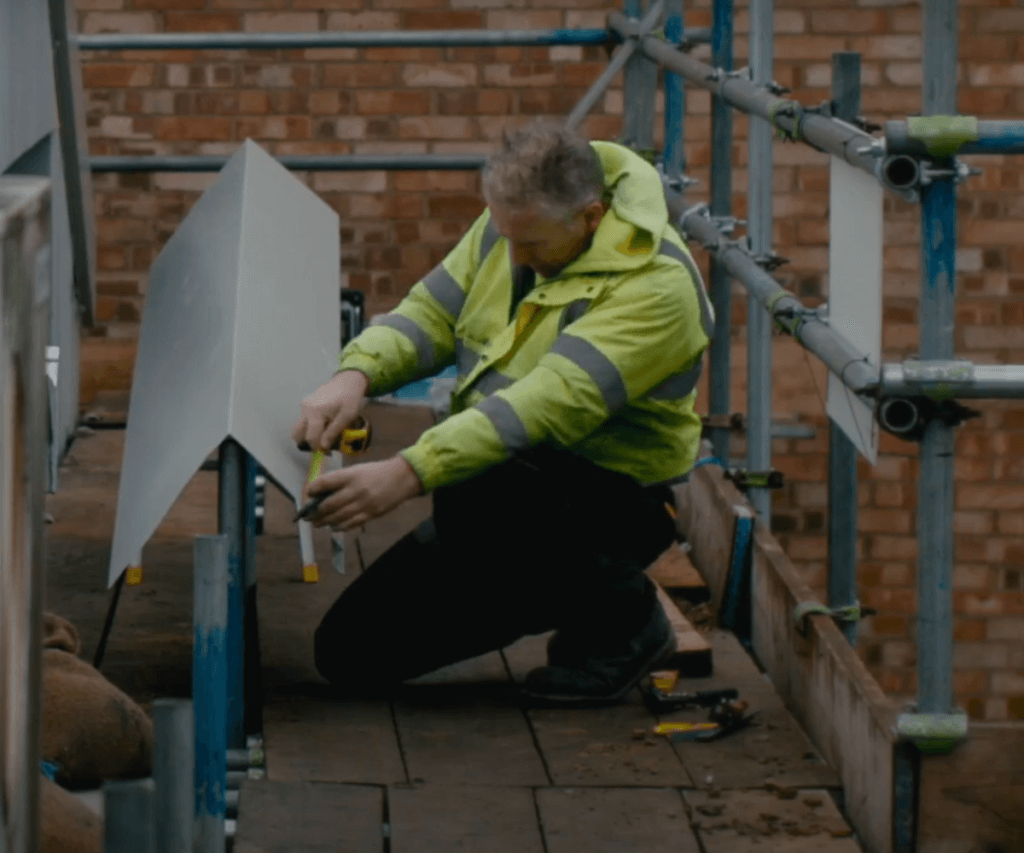 A worker carrying out energy assessment recommendations on a roof.