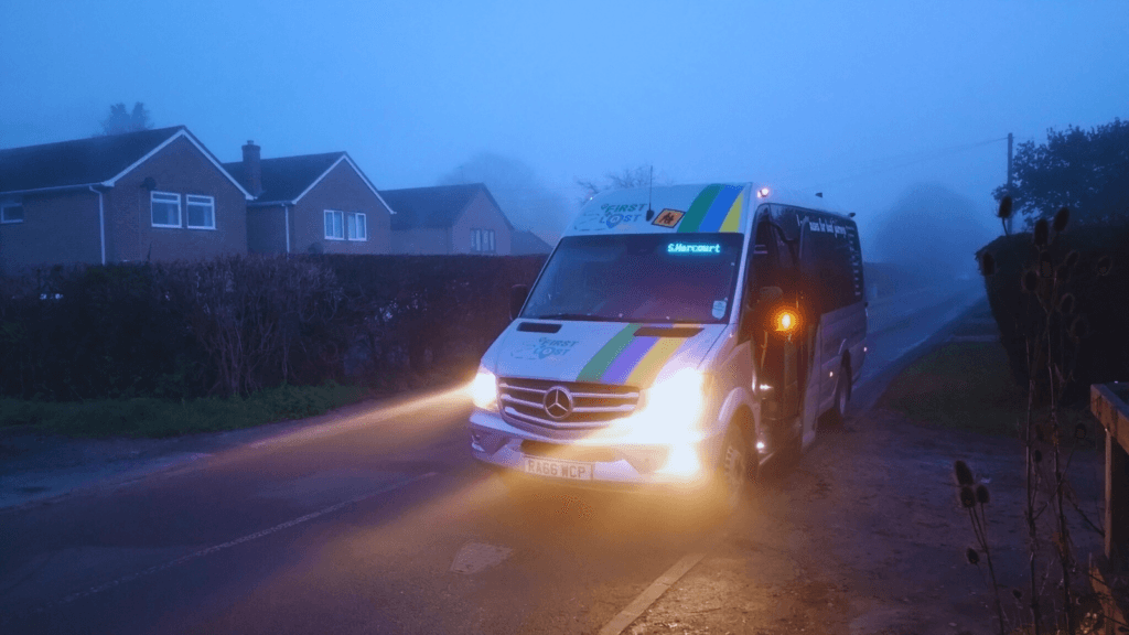 A First and Last mile bus arrives in the dusk.