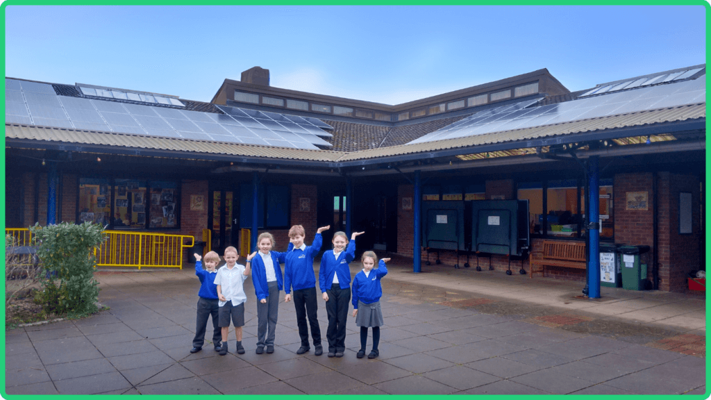 Schoolchildren pose in front of new solar panels installed on their school thanks to the Low Carbon Hub Community Energy Fund.