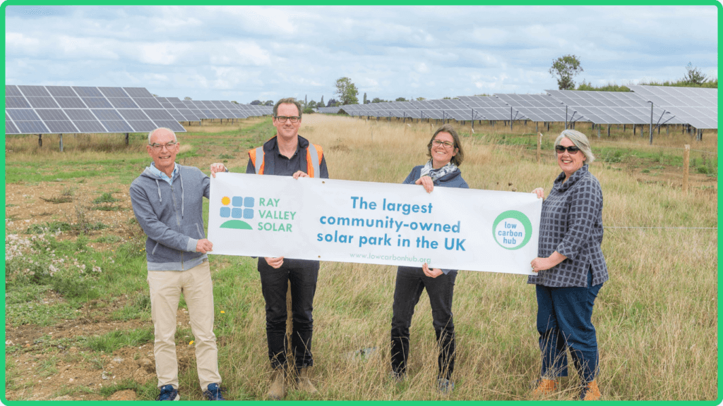 Low Carbon Hub staff hold up a sign at Ray Valley Solar Park, funded by the Community Energy Fund.